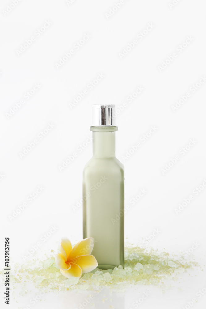 Green cosmetic bottle with bath salt and frangipani flowers Green cosmetic bottle with bath salt and frangipani flowers