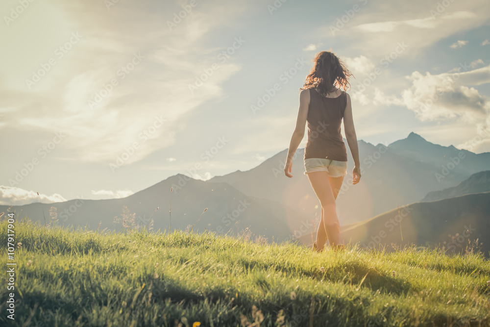 Young backside woman walk on mountain in sunny day
