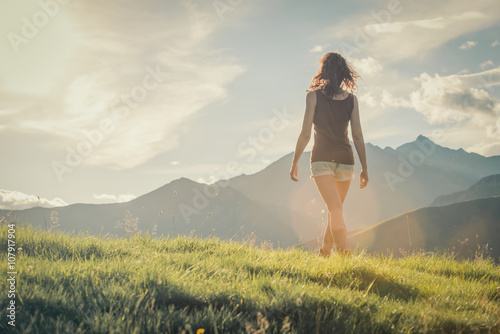 Young backside woman walk on mountain in sunny day