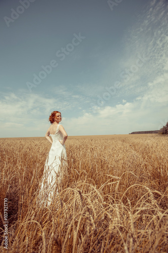 Happy red haired walking bride on the wheat field background.