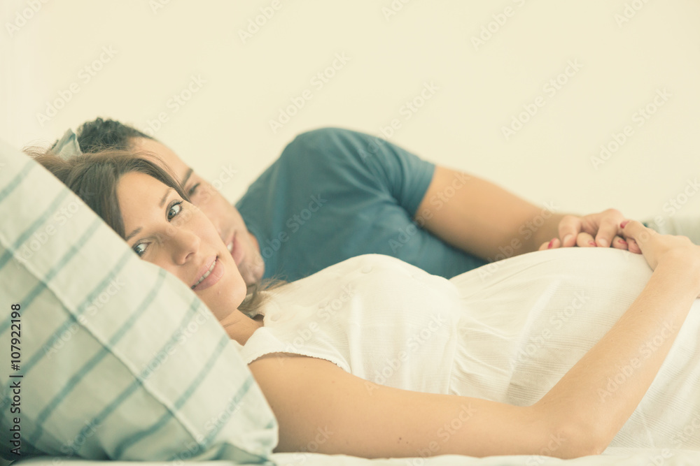 Pregnant brunette mum with husband lay in bed Pregnant brunette mum with husband lay in bed
