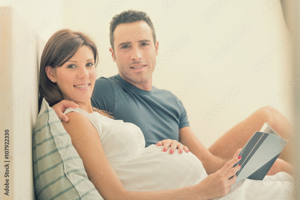 Pregnant brunette mum with husband read in bed Pregnant brunette mum with husband read in bed