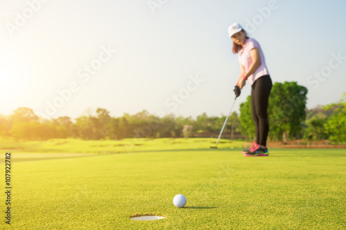 Asian woman golfer putting on green for birdie while on vacation
