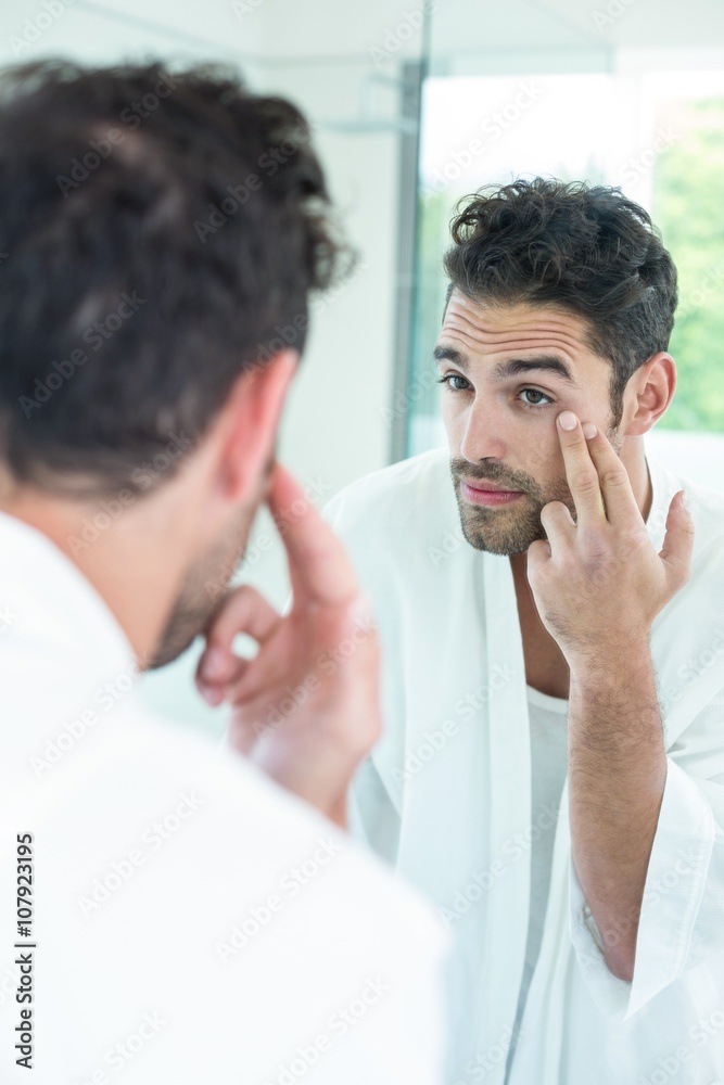 Fototapeta premium Man checking eyes in bathroom mirror