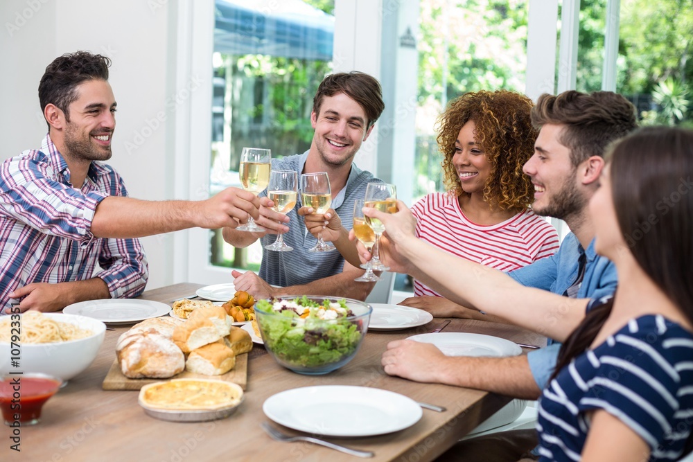 Young friends toasting wine while having meal at table Young friends toasting wine while having meal at table