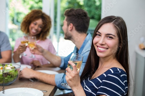 Happy young woman drinking wine with friends