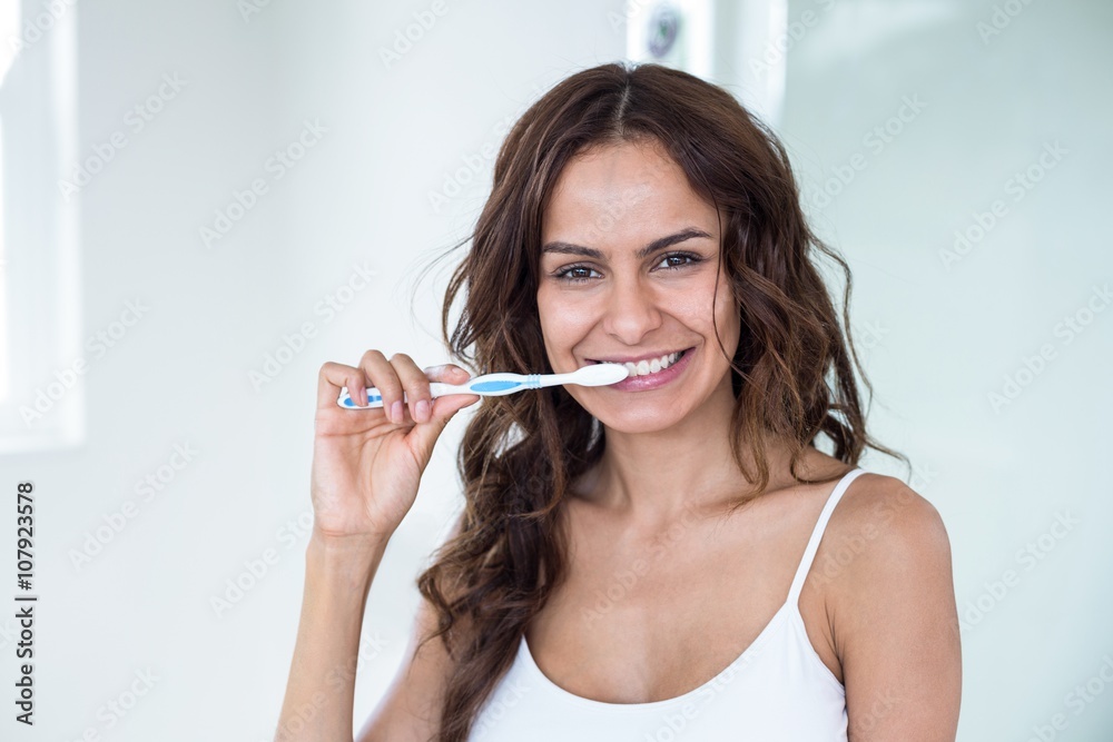 Young woman brushing teeth in bathroom