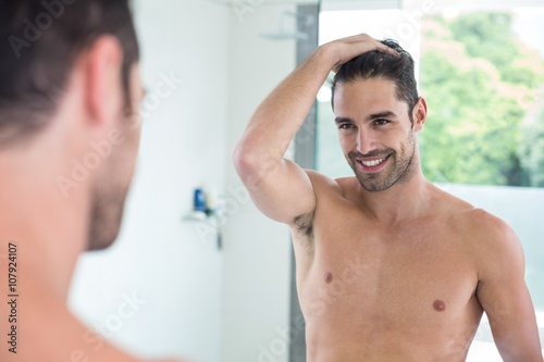 Shirtless man smiling while looking in mirror 