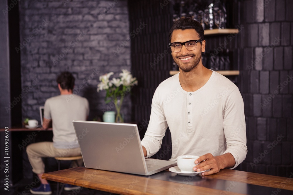 Man using a laptop and drinking coffee