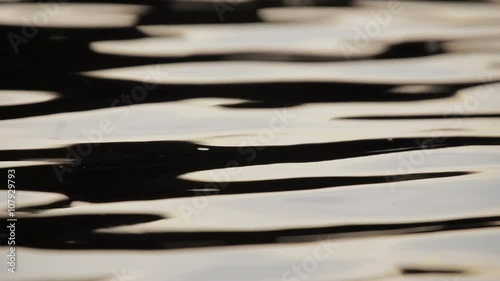 Closeup of river water at sunset in slow motion. Insects interact with the river ripples on a warm summers evening photo