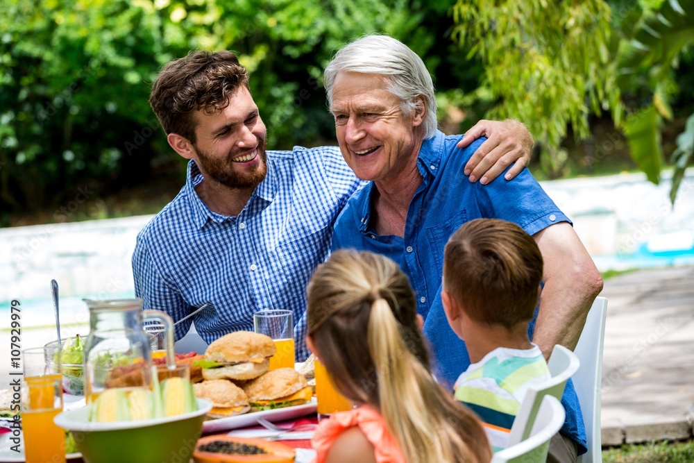 Father and son with children at dinning table in lawn Father and son with children at dinning table in lawn