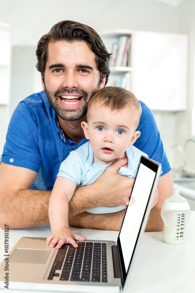 Happy father with son leaning by laptop at table Happy father with son leaning by laptop at table