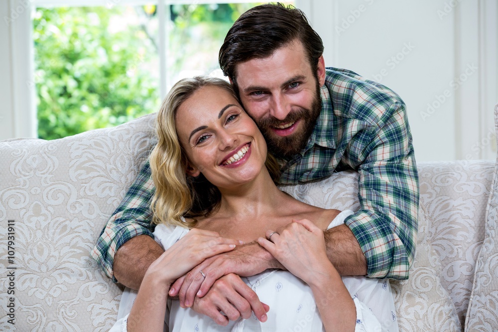 Husband embracing wife from behind against window Husband embracing wife from behind against window