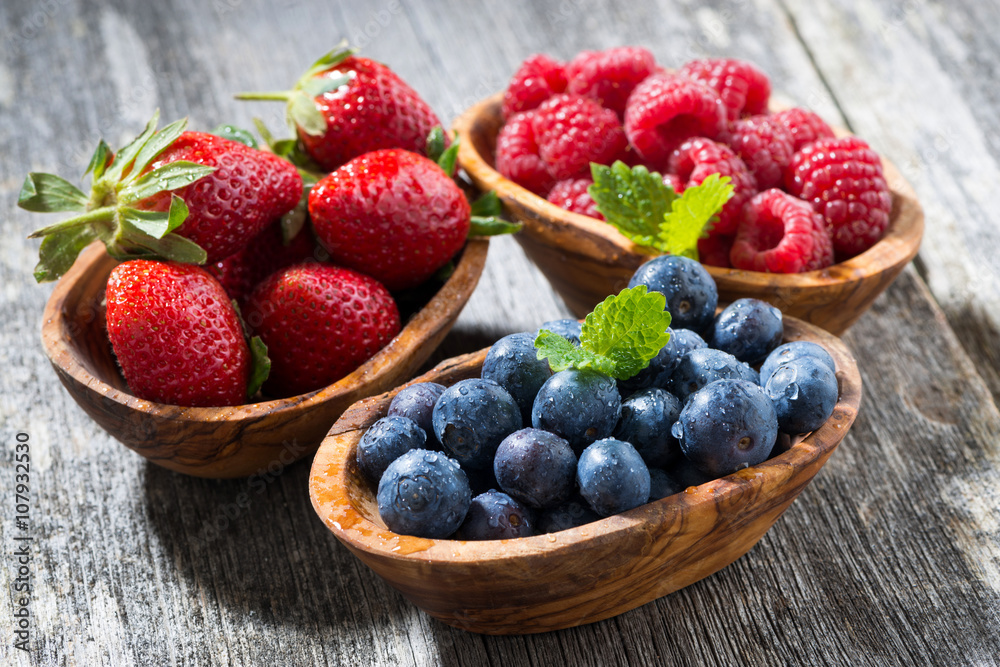 assortment of fresh seasonal berries in a wooden bowl