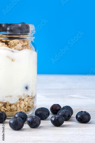 Yogurt with blueberries. Blue background
