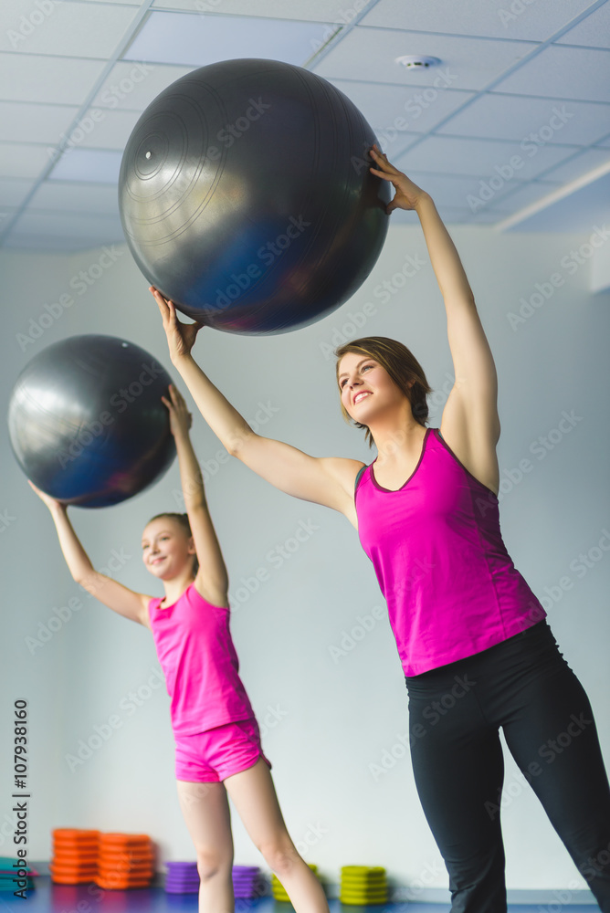 Fototapeta premium Instructor or Mother with daughter doing gymnastic exercises 