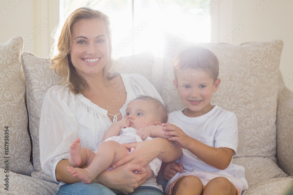 Portrait of mother sitting on sofa with her kids