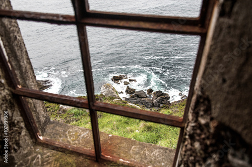 View out of an old lighthouse window down to the ocean coast