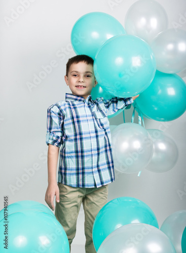 young man standing with his hands on hips, holding balloons in hands