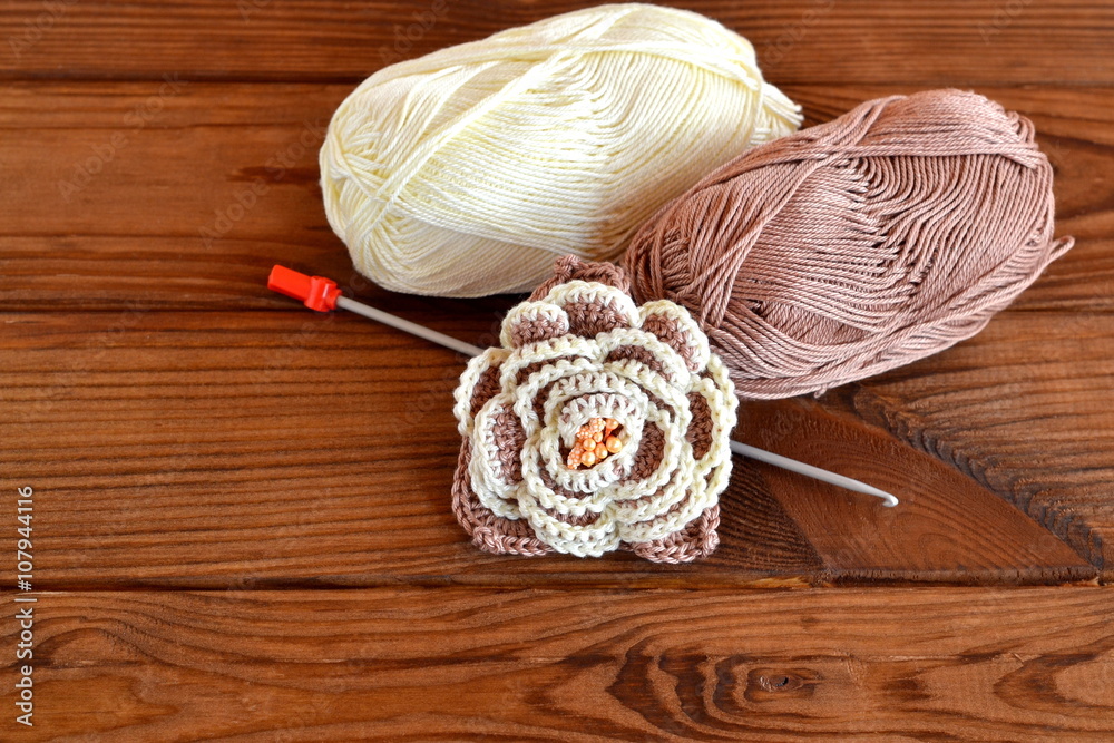 Crocheted flower, yarn on a brown wooden background Crocheted flower, yarn on a brown wooden background