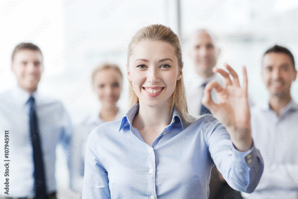 smiling businesswoman showing ok sign in office smiling businesswoman showing ok sign in office