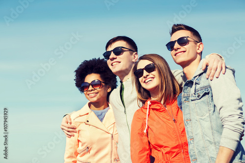 happy teenage friends in shades hugging outdoors