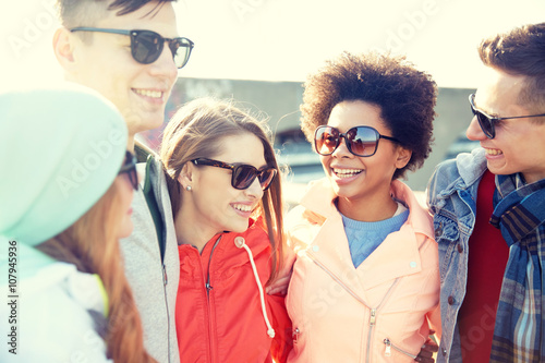 happy teenage friends in shades talking on street © Syda Productions