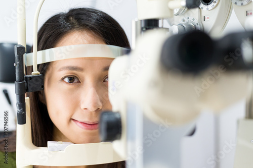 Woman look at ophthalmoscope in eye clinic