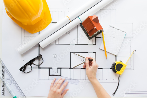 close up of hands with compass measuring blueprint