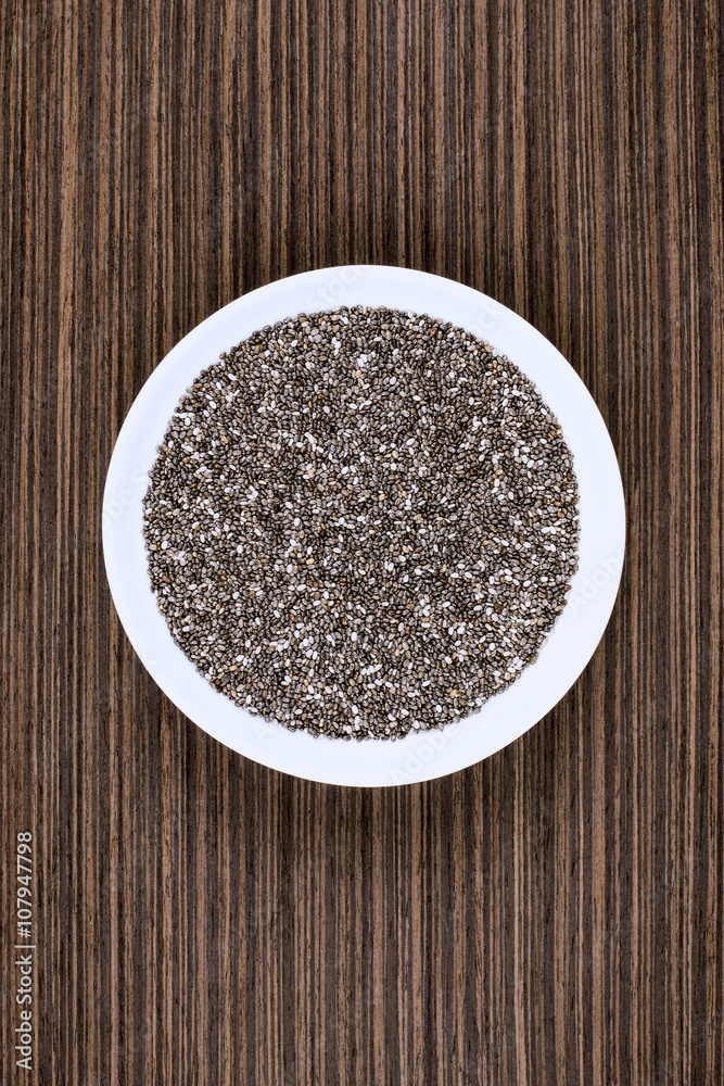 Chia seeds on white porcelain plate, wood background table. Chia seeds on white porcelain plate, wood background table.