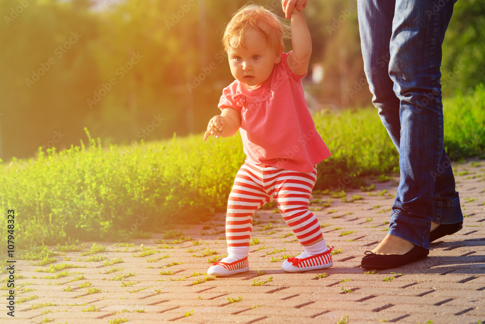 Naklejka premium first steps of little girl in summer park