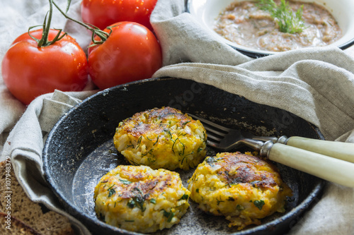 Healthy vegetarian patties made from potatoes, carrots, onions, and green on a background of tomato sauce, selective focus.