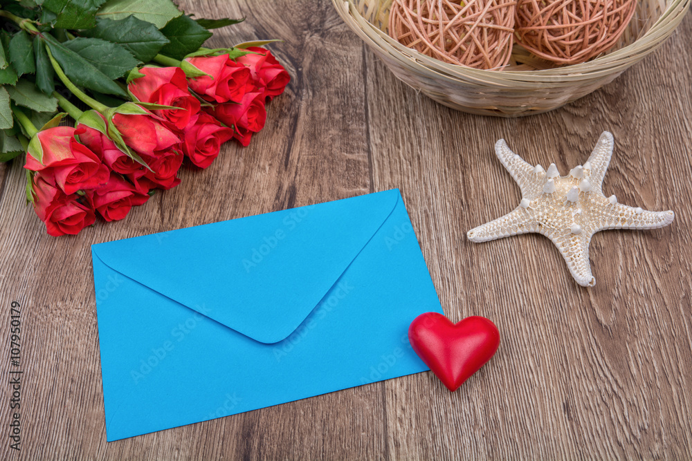 Envelope, roses and starfish on a wooden background