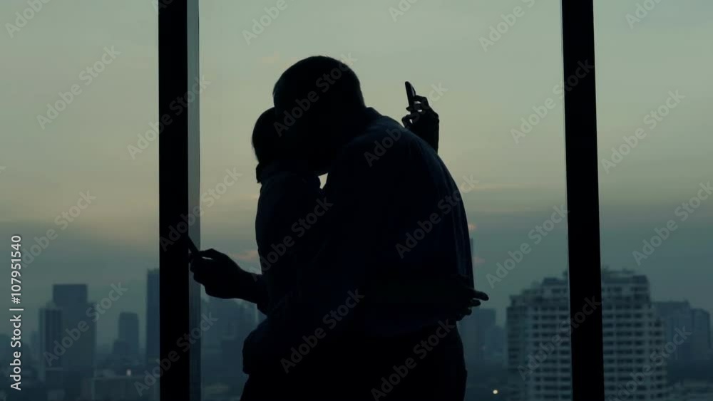 Couple staring at smartphone while hugging by window at home
Couple staring at smartphone while hugging by window at home