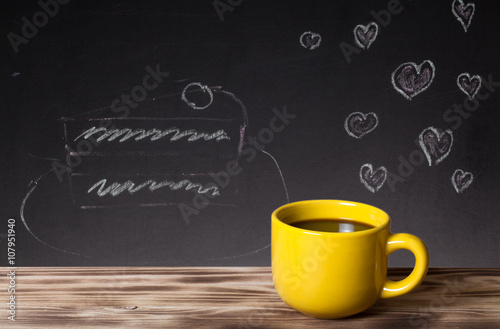 Romantic theme on a chalkboard behind a wooden table with cup of