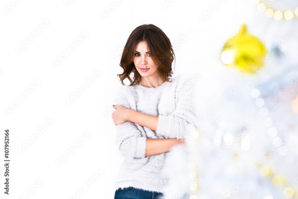 Young woman smiling looking on camera and standing near Christma