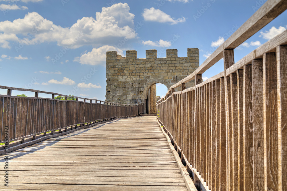 Stone walls and gate with wooden bridge on medieval fortress