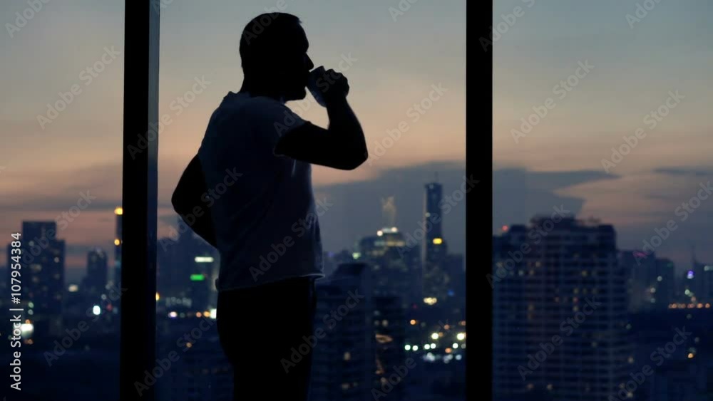 Young man drinking beverage standing by window at home at night
Young man drinking beverage standing by window at home at night