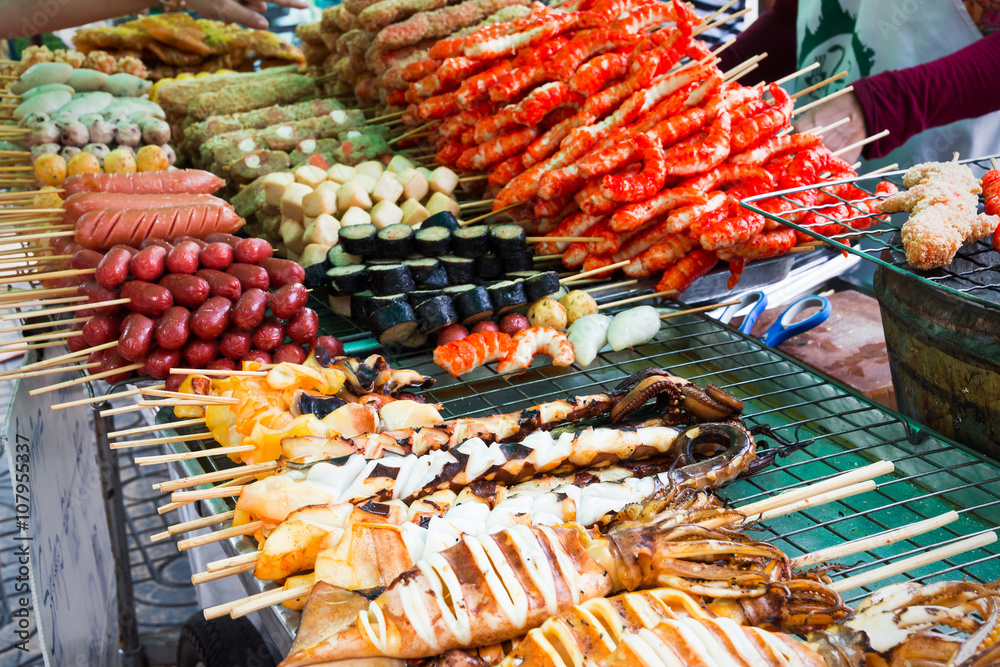 Fototapeta premium Meatballs and seafood on sticks at a market in Bangkok, Thailan