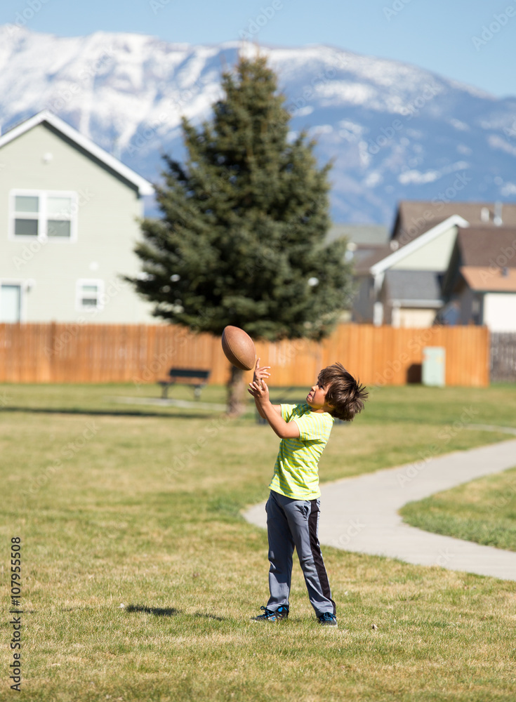 Young boy catching football.