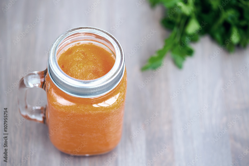 Healthy carrot smoothie in a jar on wooden background with parsley. Cold toning. Shallow dof Healthy carrot smoothie in a jar on wooden background with parsley. Cold toning. Shallow dof