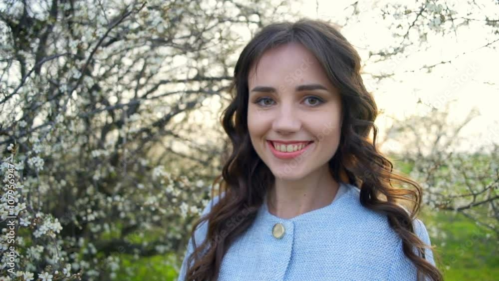 portrait of a smiling female standing under blooming tree slow motion portrait of a smiling female standing under blooming tree slow motion