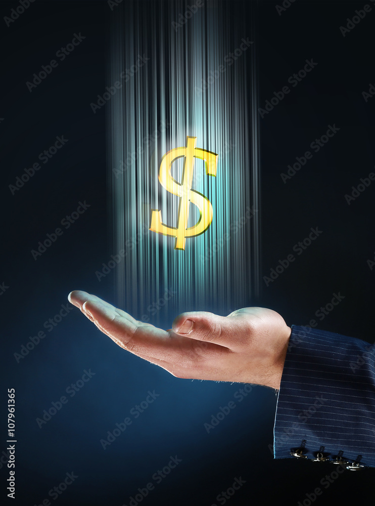 Businessman showing dollar sign in his hand, on dark background Businessman showing dollar sign in his hand, on dark background