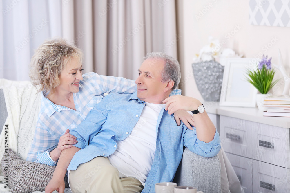 Fototapeta premium Mature couple sitting together on a sofa at home