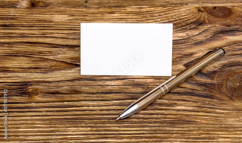 Pen with business card on wooden table