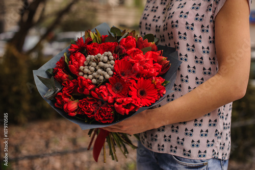 beautiful bouquet of red flowers with black paper in hands