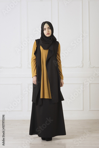 studio photo in full growth beautiful girl looks in the eastern Muslim dress and black scarf on head