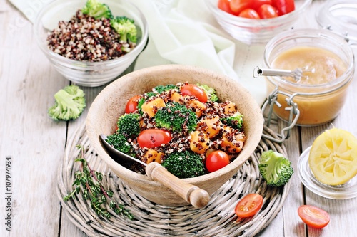 Quinoa salad with broccoli,sweet potatoes and tomatoes on a rustic wooden table.Superfoods concept.Selective focus 