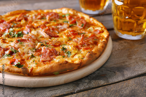 Delicious pizza and glasses of beer are on wooden table, close up