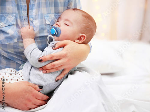 Loving baby with dummy sleeping in mother's hands, close up